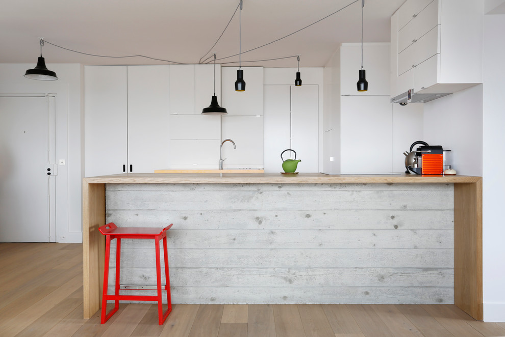 Inspiration for a mid-sized scandinavian galley open plan kitchen in Paris with flat-panel cabinets, white cabinets, a peninsula and wood benchtops.