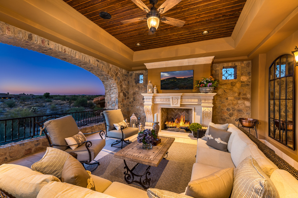 Expansive mediterranean backyard patio in Phoenix with a fire feature, natural stone pavers and a roof extension.
