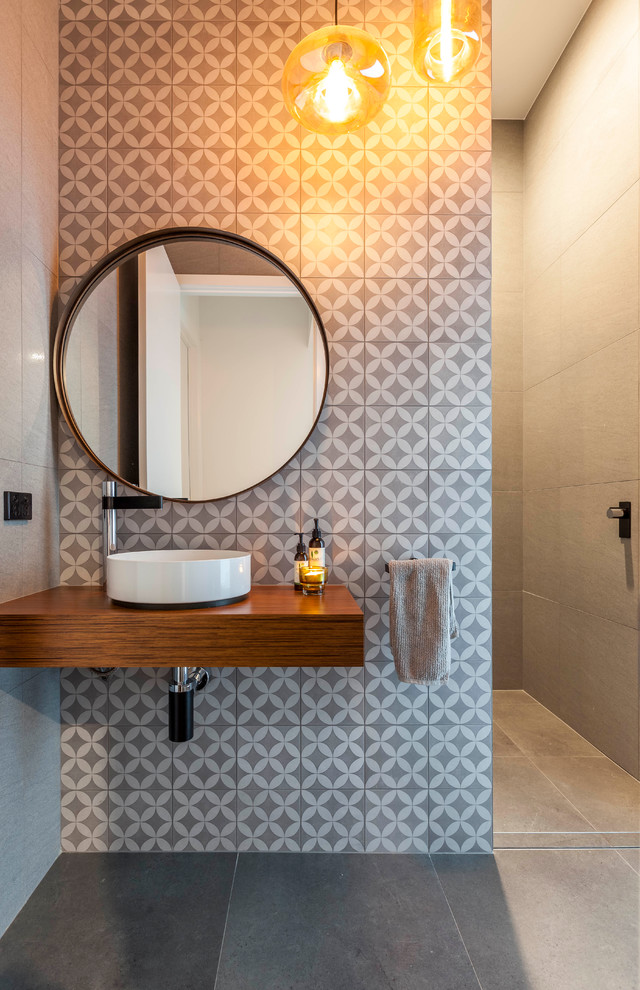 Inspiration for a mid-sized contemporary powder room in Gold Coast - Tweed with multi-coloured tile, a vessel sink, grey walls, brown benchtops and wood benchtops.