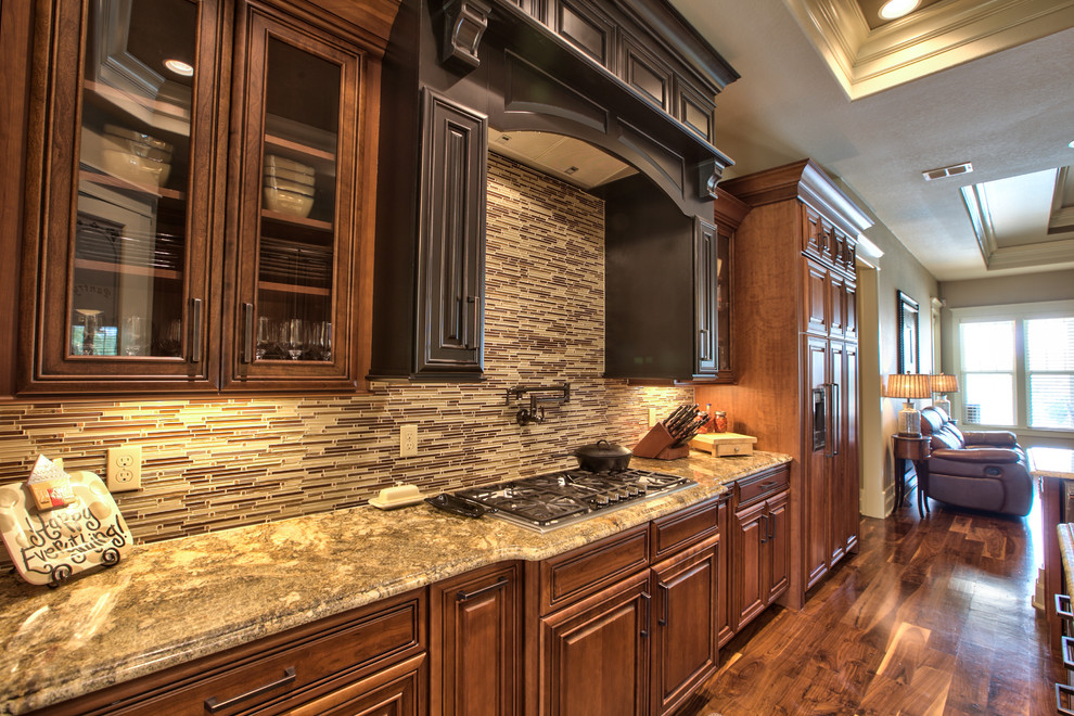 This is an example of a large arts and crafts u-shaped kitchen in Atlanta with an undermount sink, raised-panel cabinets, dark wood cabinets, granite benchtops, multi-coloured splashback, matchstick tile splashback, dark hardwood floors and with island.