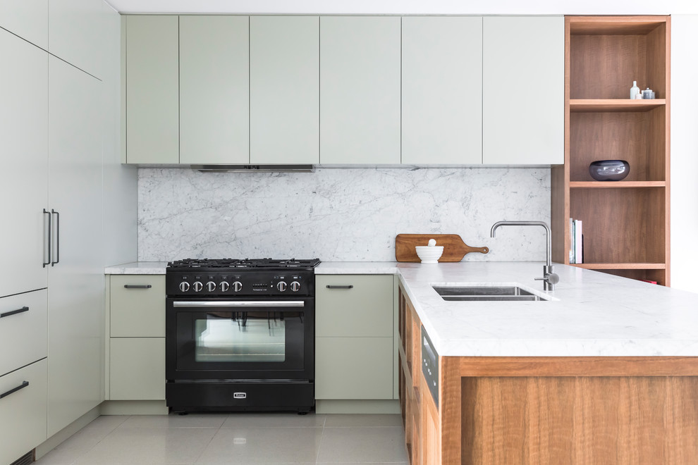 Photo of a mid-sized contemporary u-shaped open plan kitchen in Sydney with an undermount sink, shaker cabinets, medium wood cabinets, marble benchtops, white splashback, marble splashback, black appliances, porcelain floors, white floor and white benchtop.