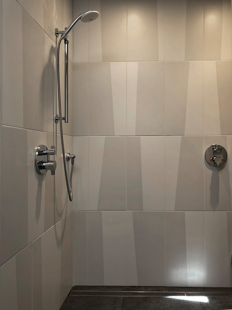 Photo of a mid-sized modern 3/4 bathroom in Seattle with glass-front cabinets, grey cabinets, a curbless shower, a wall-mount toilet, black and white tile, stone tile, white walls, porcelain floors, an integrated sink, glass benchtops, grey floor, a hinged shower door and grey benchtops.