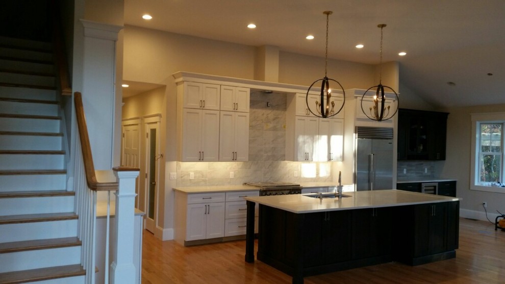 Inspiration for a transitional l-shaped medium tone wood floor eat-in kitchen remodel in Providence with an undermount sink, shaker cabinets, quartz countertops, white backsplash, porcelain backsplash, stainless steel appliances and an island