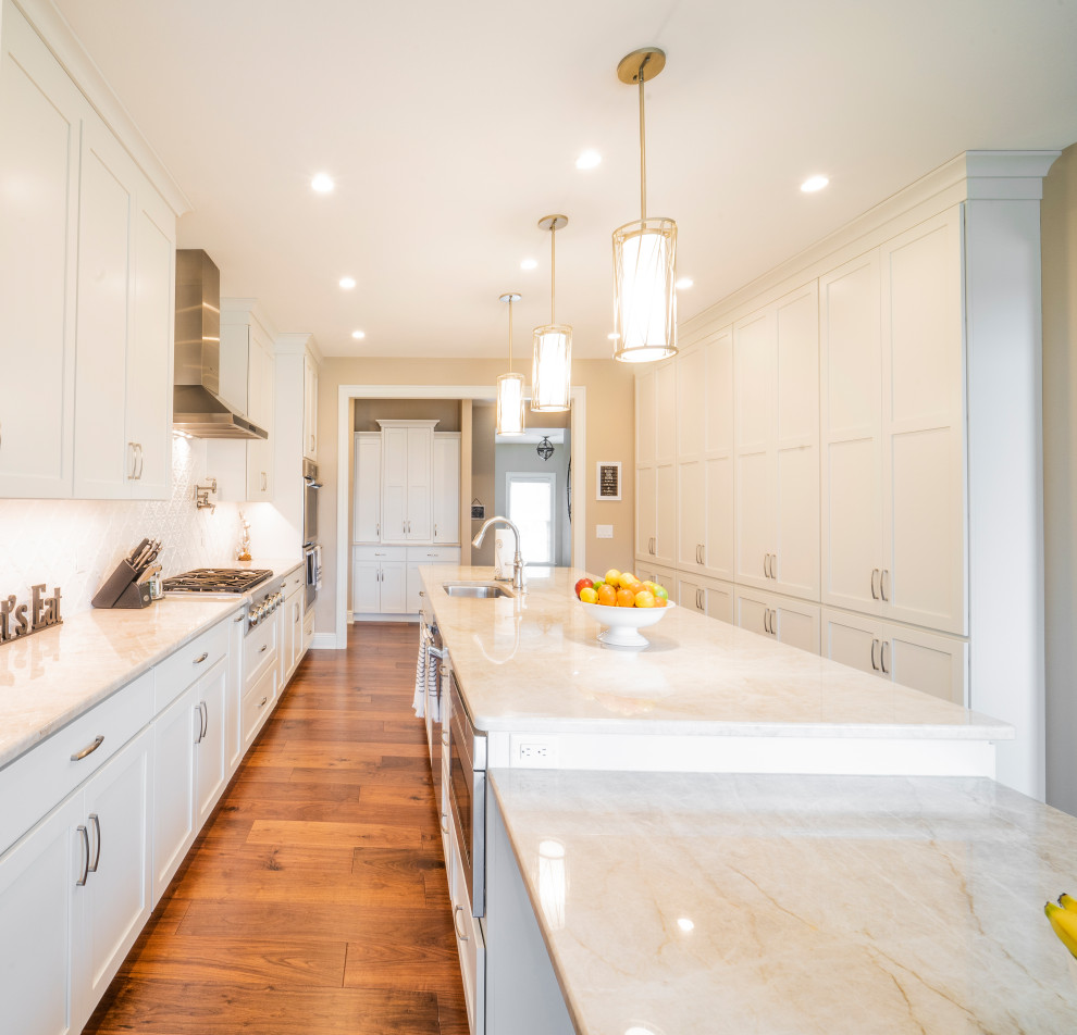 Kitchen pantry - large transitional u-shaped medium tone wood floor and brown floor kitchen pantry idea with an undermount sink, shaker cabinets, white cabinets, granite countertops, white backsplash, ceramic backsplash, stainless steel appliances, an island and white countertops