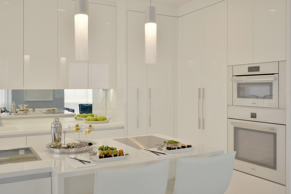 Design ideas for a small contemporary l-shaped separate kitchen in New York with an integrated sink, flat-panel cabinets, white cabinets, solid surface benchtops, mirror splashback, white appliances, porcelain floors, with island and beige floor.