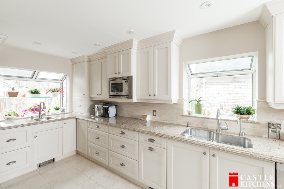 Enclosed kitchen - mid-sized transitional galley porcelain tile enclosed kitchen idea in Toronto with an undermount sink, shaker cabinets, beige cabinets, quartzite countertops, beige backsplash, stainless steel appliances and an island