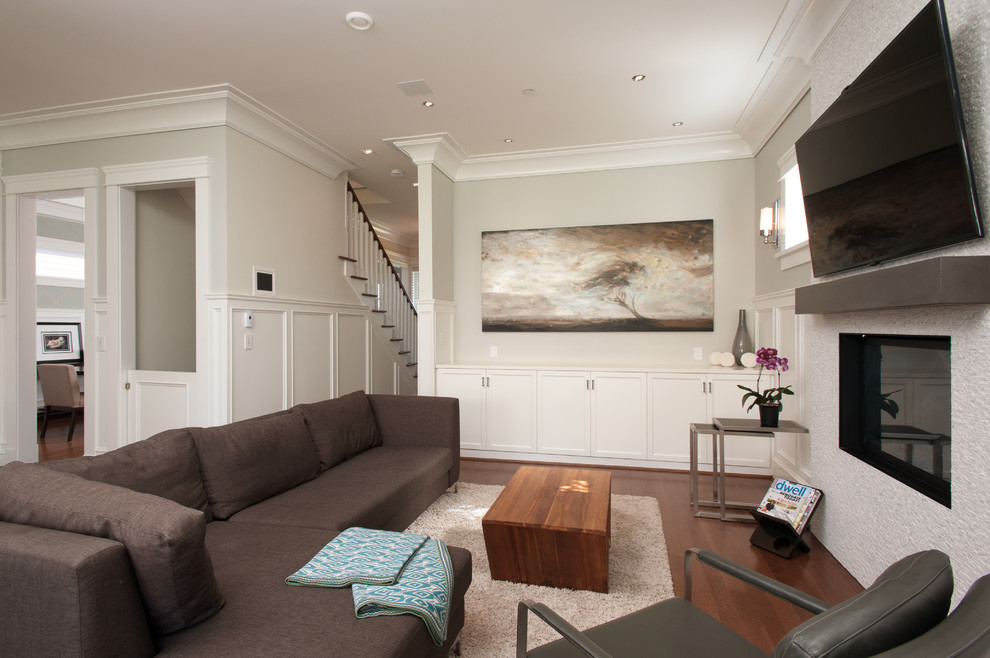 This is an example of a mid-sized arts and crafts open concept family room in Vancouver with grey walls, medium hardwood floors, a standard fireplace, a tile fireplace surround and a wall-mounted tv.
