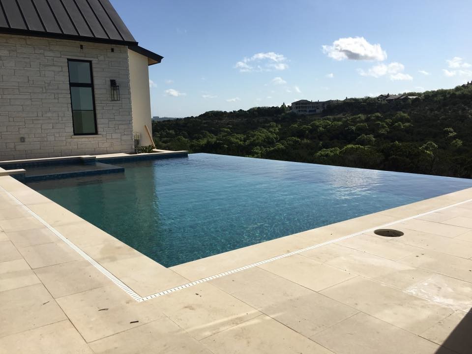Inspiration for a large modern backyard concrete and rectangular infinity hot tub remodel in Austin