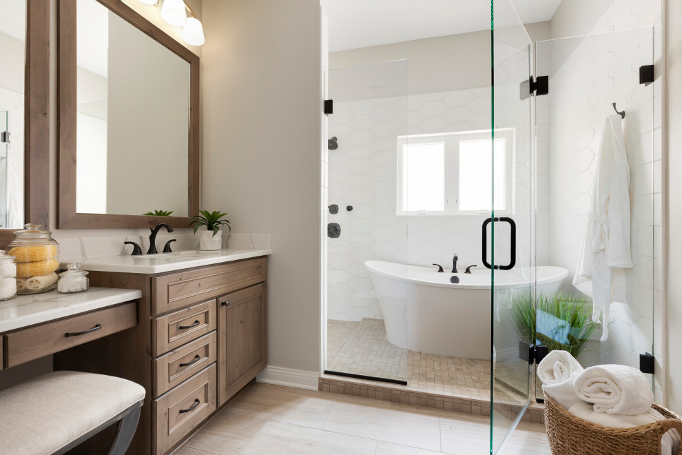 Photo of a large transitional master wet room bathroom in Minneapolis with medium wood cabinets, a freestanding tub, white tile, grey walls, light hardwood floors, an undermount sink, beige floor, a hinged shower door, white benchtops and recessed-panel cabinets.