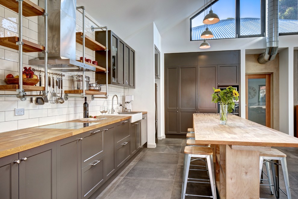 Design ideas for a small industrial l-shaped open plan kitchen in Adelaide with a farmhouse sink, shaker cabinets, grey cabinets, wood benchtops, white splashback, subway tile splashback, stainless steel appliances, ceramic floors, with island and grey floor.