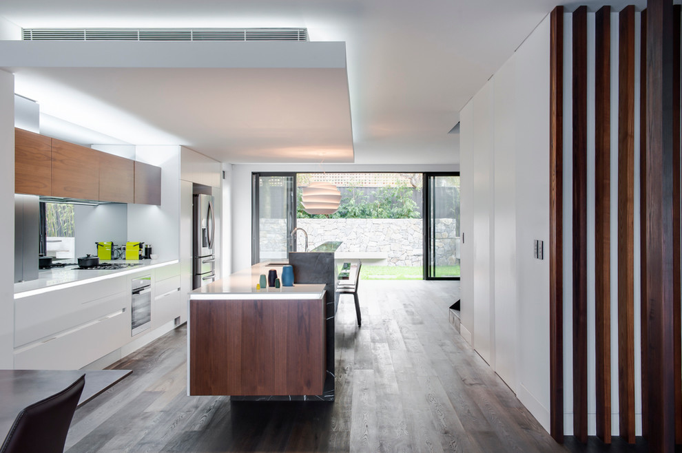 Design ideas for a mid-sized contemporary eat-in kitchen in Sydney with an undermount sink, medium wood cabinets, solid surface benchtops, mirror splashback, stainless steel appliances, dark hardwood floors and with island.