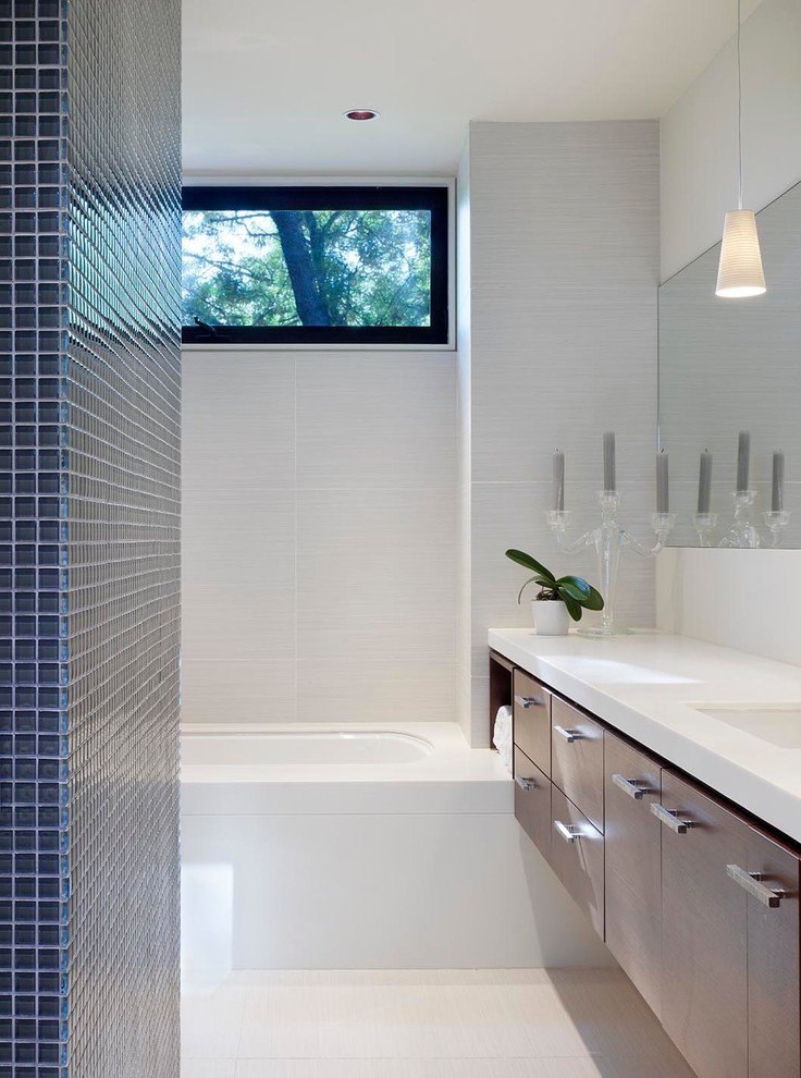 Design ideas for a mid-sized contemporary kids bathroom in Toronto with an undermount sink, flat-panel cabinets, dark wood cabinets, solid surface benchtops, an undermount tub, an alcove shower, a one-piece toilet, blue tile, white walls and porcelain floors.