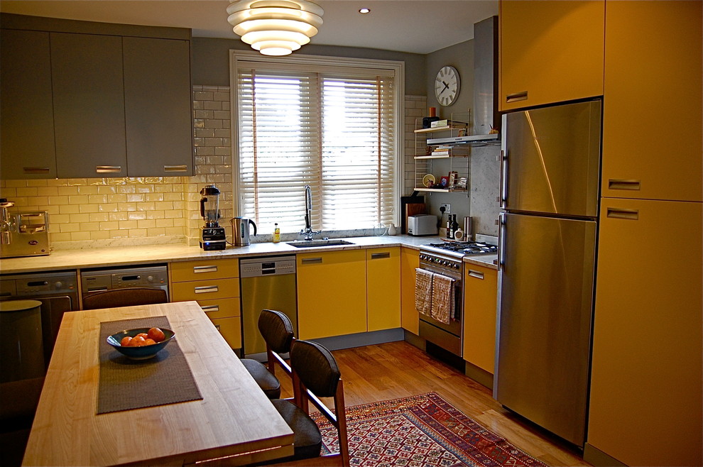 Design ideas for a large contemporary l-shaped eat-in kitchen in London with an undermount sink, flat-panel cabinets, yellow cabinets, quartz benchtops, white splashback, subway tile splashback, stainless steel appliances, medium hardwood floors and no island.