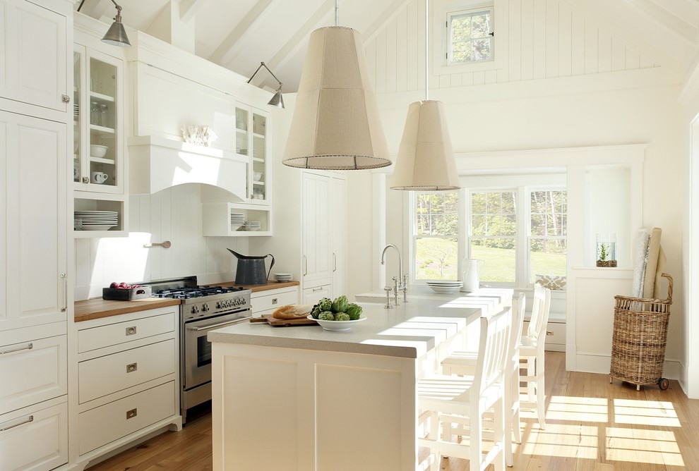 This is an example of a beach style galley kitchen in Boston with raised-panel cabinets, white cabinets, concrete benchtops, white splashback and panelled appliances.