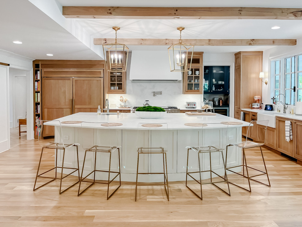 Town + Country Addition and Renovation - Our clients wanted a kitchen that could keep up with their family's pace. They love watching cooking competitions and wanted their kitchen to be the perfect spot for their kids to have cookie bake-offs. To make that possible, their kitchen needed to be wider, more capable, and more open than their current one, while still feeling connected to the family room. The wife wanted to be present with her family even while cooking, with a clear view of both the breakfast room and the family room wherever she stood. That sightline became the guiding principle for the entire space.

What came together is nothing short of a dream kitchen. The footprint was dramatically expanded as part of the addition, anchored by an oversized island with a bright quartz countertop that invites the whole family to pull up a stool and stay a while. Warm, natural wood cabinetry wraps the perimeter, grounding the space with richness and texture, while the white island keeps everything feeling bright and open. Exposed wood beams overhead carry warmth upward, and a pair of brass lantern pendants over the island add just the right amount of drama without competing with the natural light pouring in through the wall of windows in the breakfast room.

The butler's pantry, tucked just off the kitchen, adds the kind of storage and prep space that makes a busy household run smoothly, and gives the whole cooking experience a sense of ease and luxury that the family now wonders how they ever lived without. And with the family room and breakfast room always in view, separated only by open air, this kitchen doesn't just function beautifully. It draws everyone together exactly the way our clients always hoped it would.