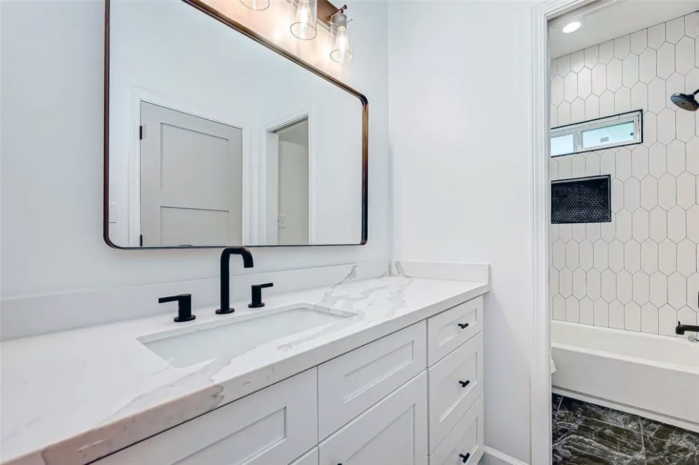 Inspiration for a mid-sized black and white tile and marble tile marble floor, black floor and single-sink tub/shower combo remodel with white cabinets, white walls, quartzite countertops, white countertops and a built-in vanity