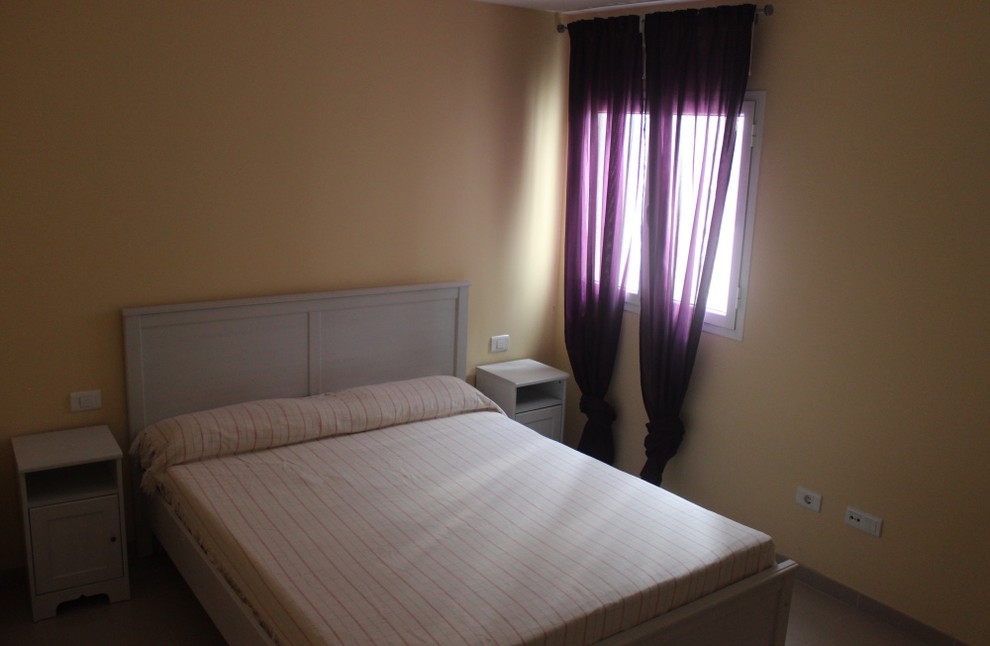 Foto de dormitorio principal tradicional renovado de tamaño medio sin chimenea con paredes amarillas y suelo de baldosas de cerámica