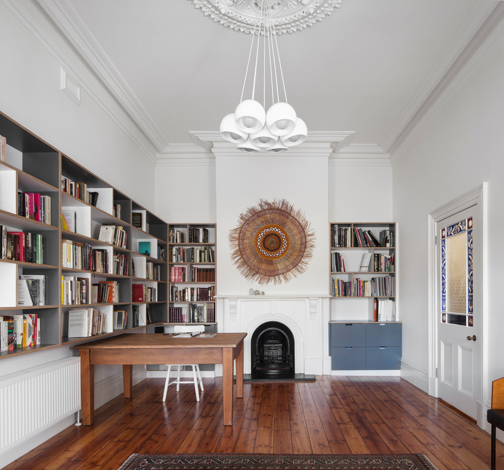 Mid-sized scandinavian study room in Melbourne with a standard fireplace, a wood fireplace surround, a freestanding desk, white walls and dark hardwood floors.