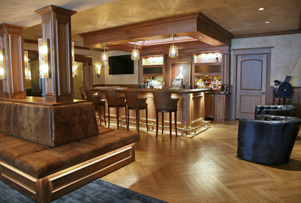 Immagine di un grande bancone bar classico con ante con bugna sagomata, ante in legno bruno, top in granito, paraspruzzi marrone, paraspruzzi in legno, parquet chiaro e top nero