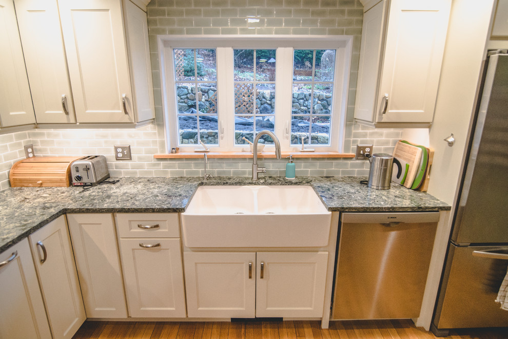 Inspiration for a mid-sized traditional l-shaped eat-in kitchen in Boston with a double-bowl sink, white cabinets, quartz benchtops, grey splashback, ceramic splashback, stainless steel appliances, medium hardwood floors, with island and brown floor.