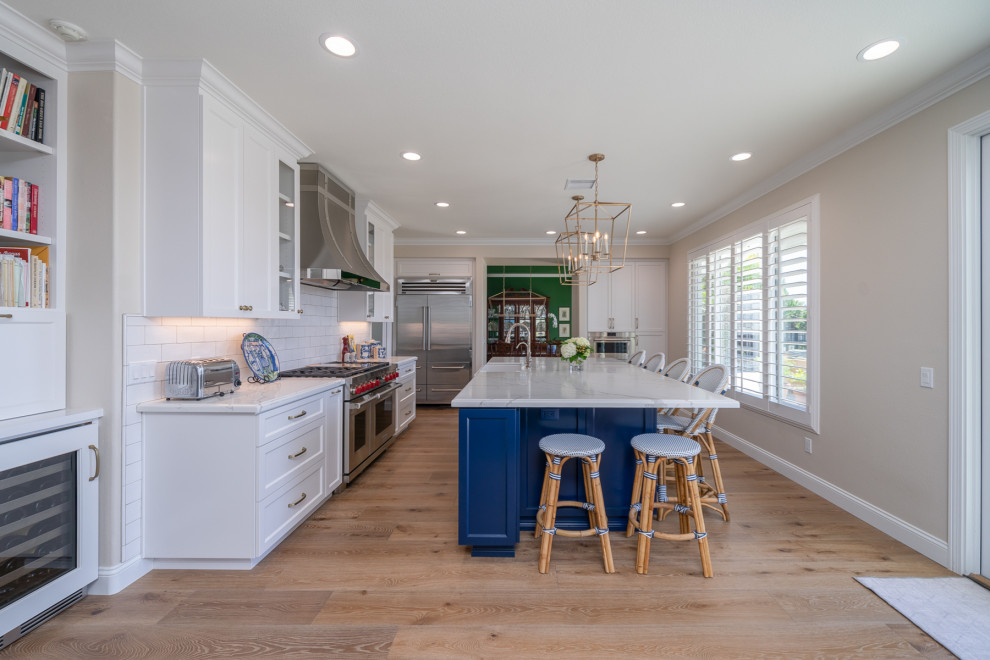 Exempel på ett stort modernt vit vitt kök, med en integrerad diskho, luckor med infälld panel, vita skåp, bänkskiva i kvarts, vitt stänkskydd, stänkskydd i tunnelbanekakel, rostfria vitvaror, ljust trägolv, en köksö och brunt golv