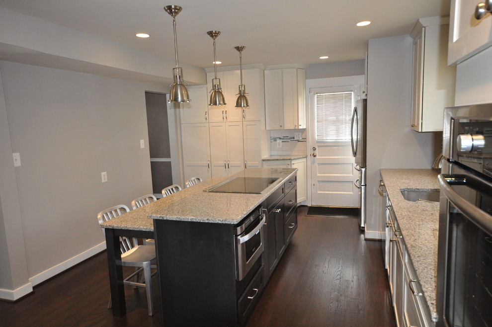 Example of a mid-sized transitional l-shaped dark wood floor and brown floor open concept kitchen design in DC Metro with an undermount sink, shaker cabinets, white cabinets, white backsplash, subway tile backsplash, stainless steel appliances and an island