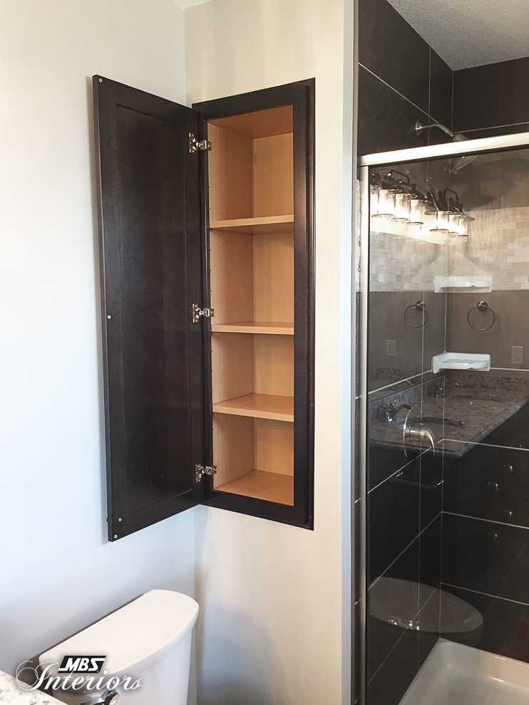 Photo of a mid-sized arts and crafts master bathroom in Other with shaker cabinets, dark wood cabinets, grey walls, an undermount sink, granite benchtops, an alcove shower, a one-piece toilet, black and white tile, ceramic tile, ceramic floors, grey floor and a hinged shower door.