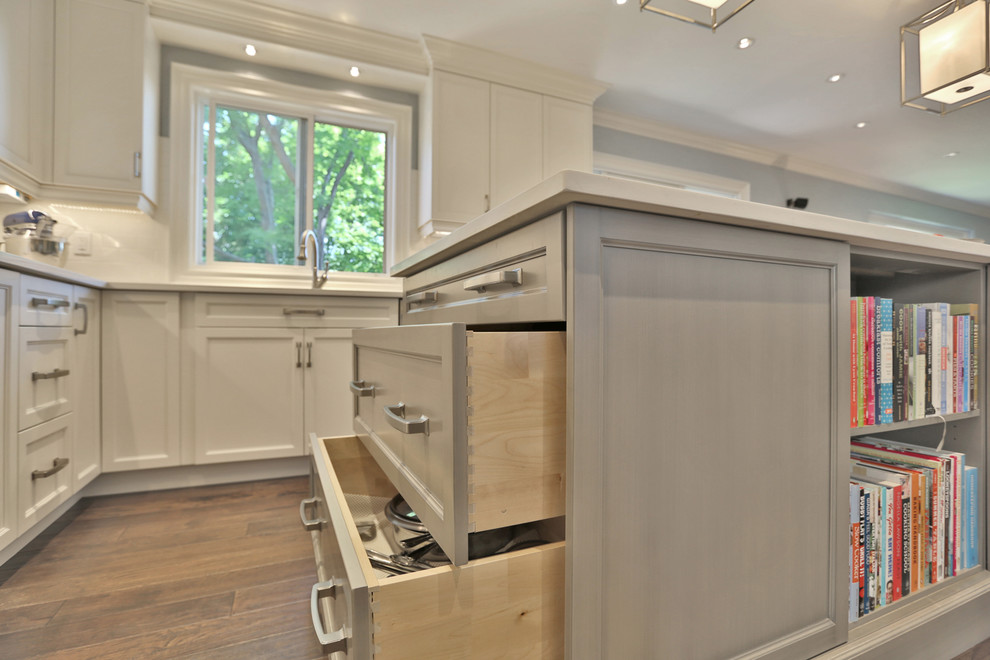 Design ideas for a large traditional open plan kitchen in Toronto with an undermount sink, shaker cabinets, white cabinets, quartzite benchtops, white splashback, dark hardwood floors and with island.