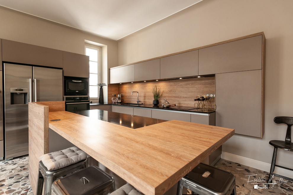 Idées déco pour cuisine américaine in U With un évier encastré, un placard à porte affleurante, des portes de placard grises, un plan de travail en quartz modifié, une crédence marron, une crédence en bois, un électroménager en acier inoxydable, carreaux de ciment au sol, îlot, un sol multicolore and plan de travail noir.