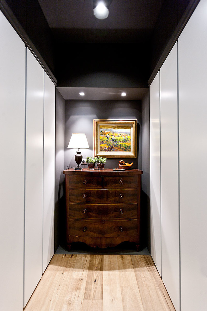 Inspiration for a mid-sized transitional gender-neutral walk-in wardrobe in Other with flat-panel cabinets, white cabinets and light hardwood floors.