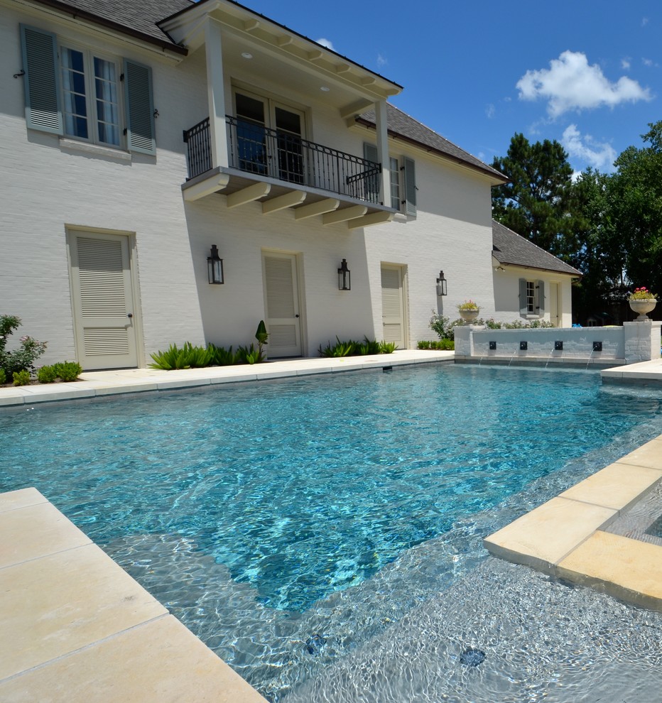 Design ideas for a mid-sized eclectic backyard custom-shaped lap pool in New Orleans with a water feature and natural stone pavers.