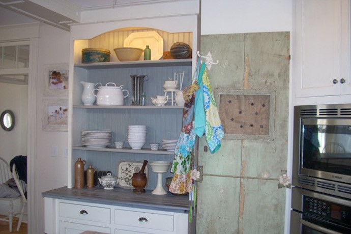 Large transitional l-shaped travertine floor and beige floor eat-in kitchen photo in Boston with a farmhouse sink, recessed-panel cabinets, white cabinets, granite countertops, white backsplash, subway tile backsplash, paneled appliances, an island and black countertops