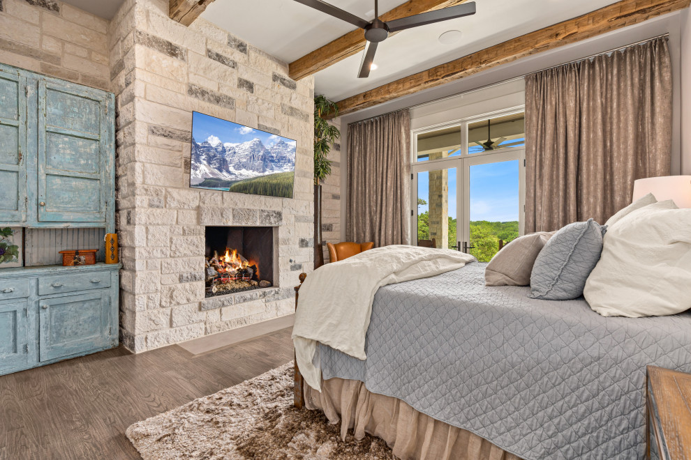 Design ideas for an expansive country master bedroom in Other with a standard fireplace, a stone fireplace surround and exposed beam.