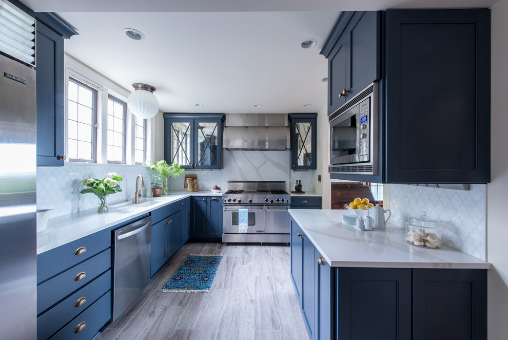 Design ideas for a mid-sized traditional galley separate kitchen in Seattle with an undermount sink, shaker cabinets, blue cabinets, quartz benchtops, white splashback, glass tile splashback, stainless steel appliances, porcelain floors and with island.