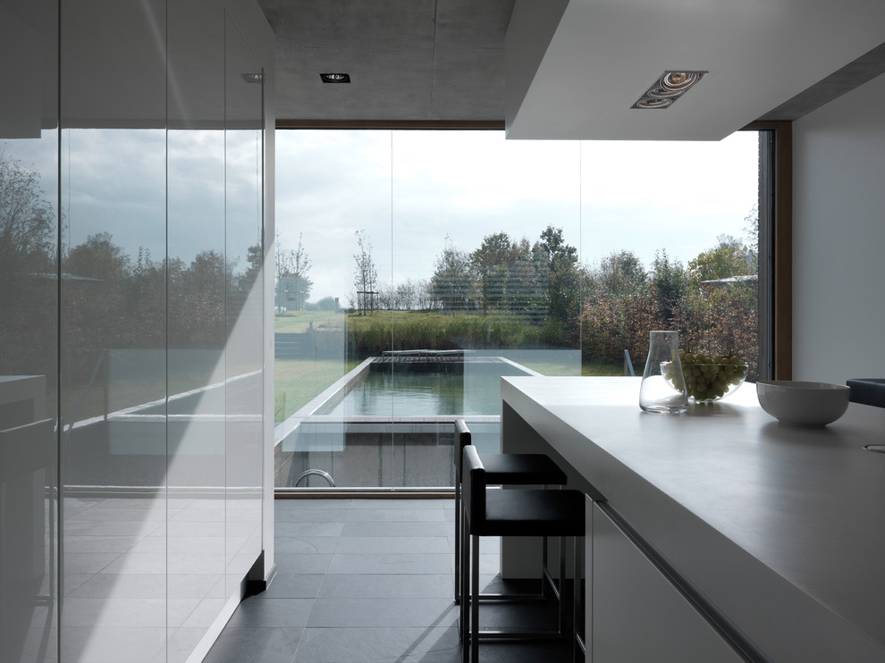 Geschlossene, Mittelgroße Moderne Küche mit flächenbündigen Schrankfronten, weißen Schränken, Schieferboden und Kücheninsel in Stuttgart