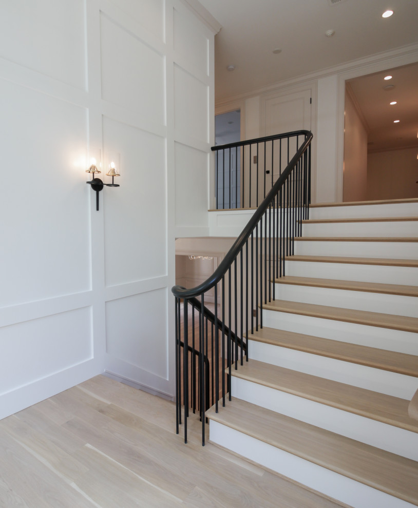 Cette image montre un grand escalier peint minimaliste en U avec des marches en bois, un garde-corps en matériaux mixtes, boiseries et palier.