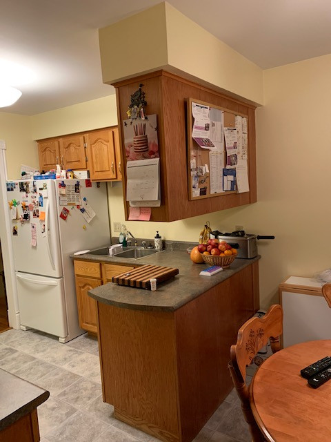 Enclosed kitchen - mid-sized transitional galley enclosed kitchen idea with a drop-in sink, raised-panel cabinets, medium tone wood cabinets, laminate countertops, white appliances, a peninsula and gray countertops