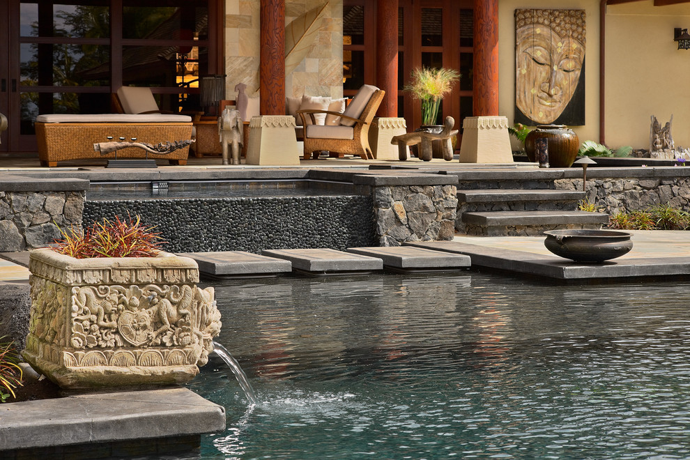 Inspiration for a mid-sized asian rectangular infinity pool in Hawaii with natural stone pavers.