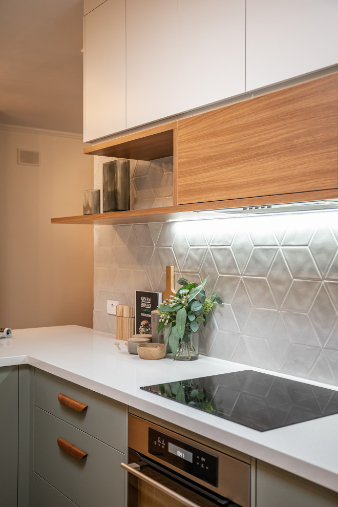 Example of a mid-sized trendy galley light wood floor kitchen pantry design in Adelaide with an undermount sink, flat-panel cabinets, green cabinets, quartz countertops, gray backsplash, porcelain backsplash, stainless steel appliances, a peninsula and white countertops