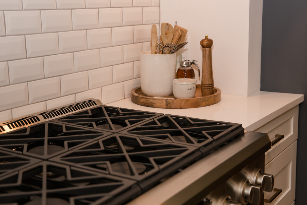 Mid-sized transitional galley medium tone wood floor and brown floor eat-in kitchen photo with an undermount sink, shaker cabinets, white cabinets, solid surface countertops, white backsplash, ceramic backsplash, stainless steel appliances, a peninsula and white countertops