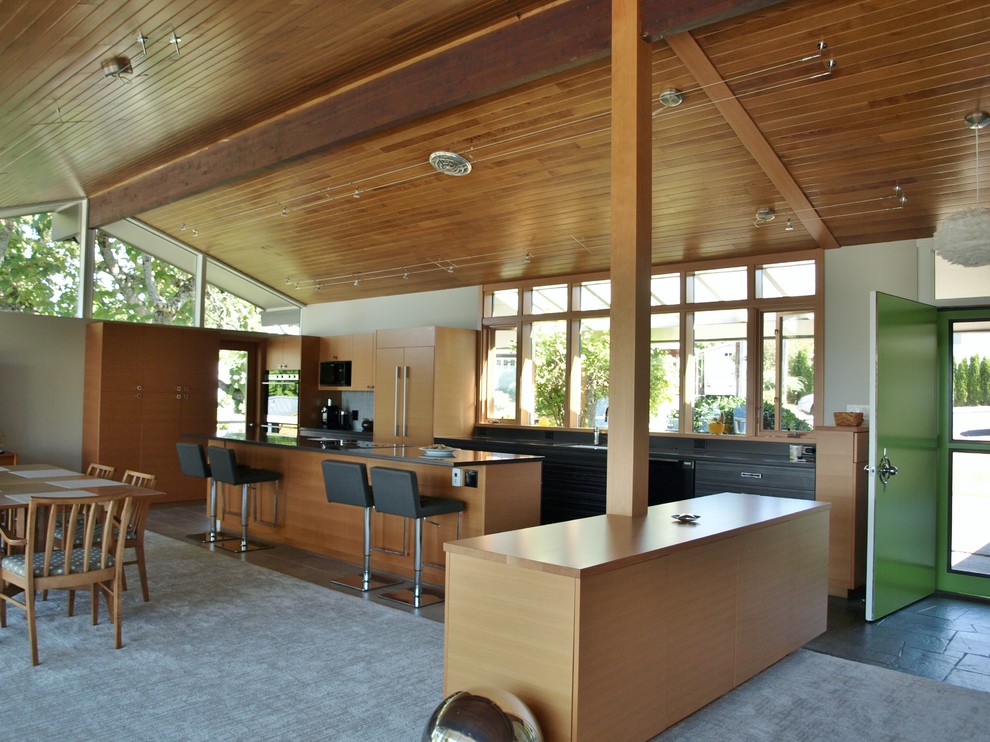 Inspiration for a mid-sized midcentury galley eat-in kitchen in Seattle with a double-bowl sink, flat-panel cabinets, medium wood cabinets, quartz benchtops, grey splashback, ceramic splashback, black appliances, ceramic floors and with island.