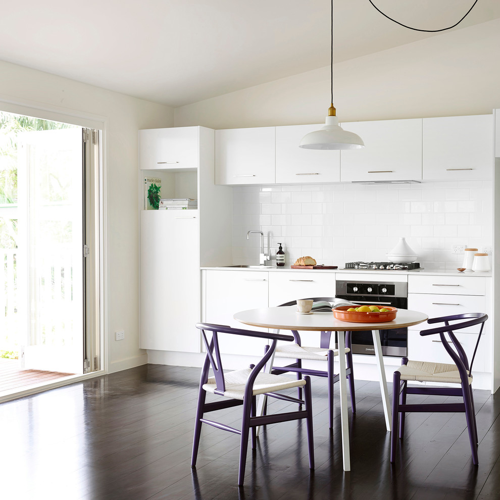 Photo of a scandinavian single-wall eat-in kitchen in Brisbane with a single-bowl sink, white cabinets, quartz benchtops, white splashback, ceramic splashback, stainless steel appliances, painted wood floors and no island.