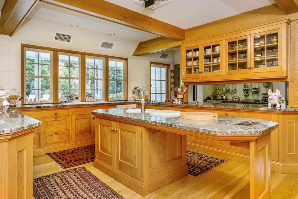 Mid-sized transitional u-shaped light wood floor kitchen photo with a drop-in sink, glass-front cabinets, light wood cabinets, granite countertops and an island