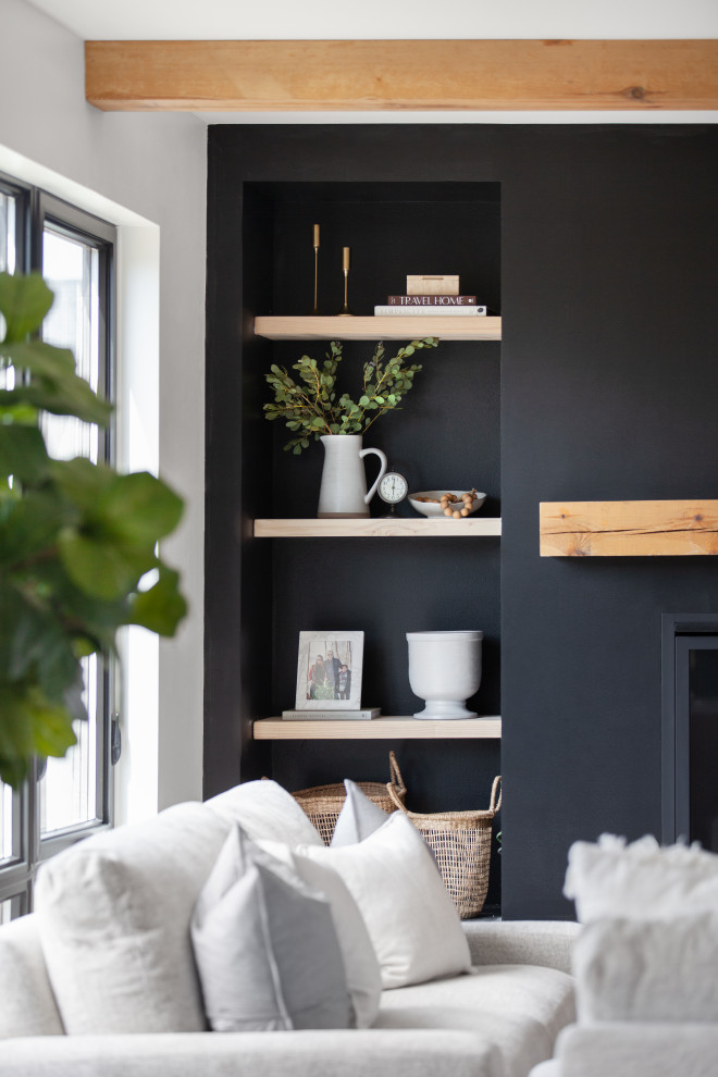 Стильный дизайн: гостиная комната в скандинавском стиле с черными стенами, светлым паркетным полом, стандартным камином и балками на потолке - последний тренд