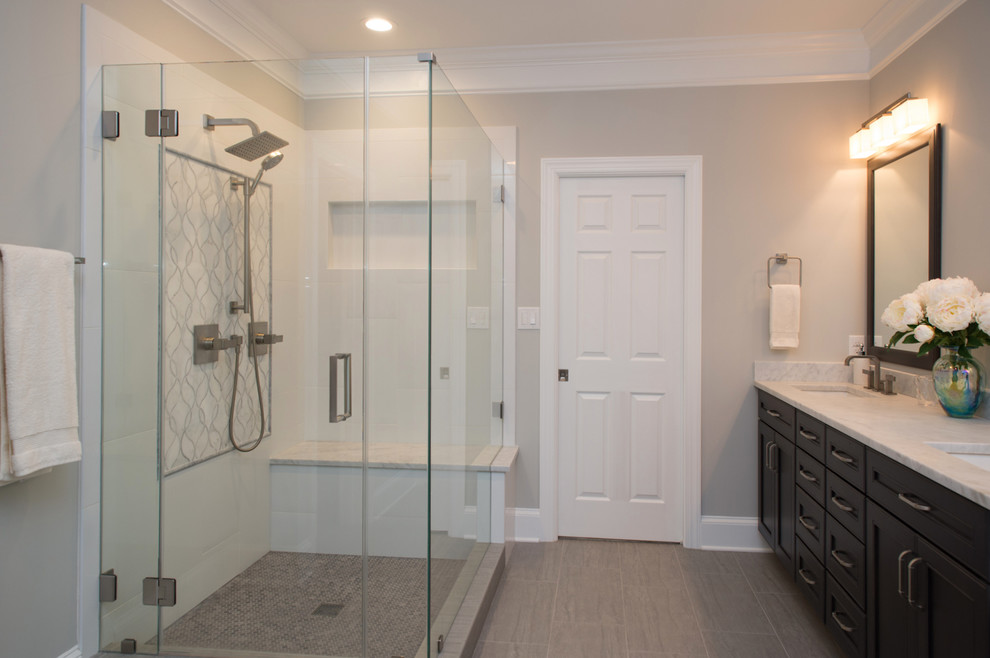 Mid-sized transitional master bathroom in Charlotte with beaded inset cabinets, dark wood cabinets, a freestanding tub, a corner shower, a two-piece toilet, white tile, porcelain tile, grey walls, porcelain floors, an undermount sink, marble benchtops and a hinged shower door.