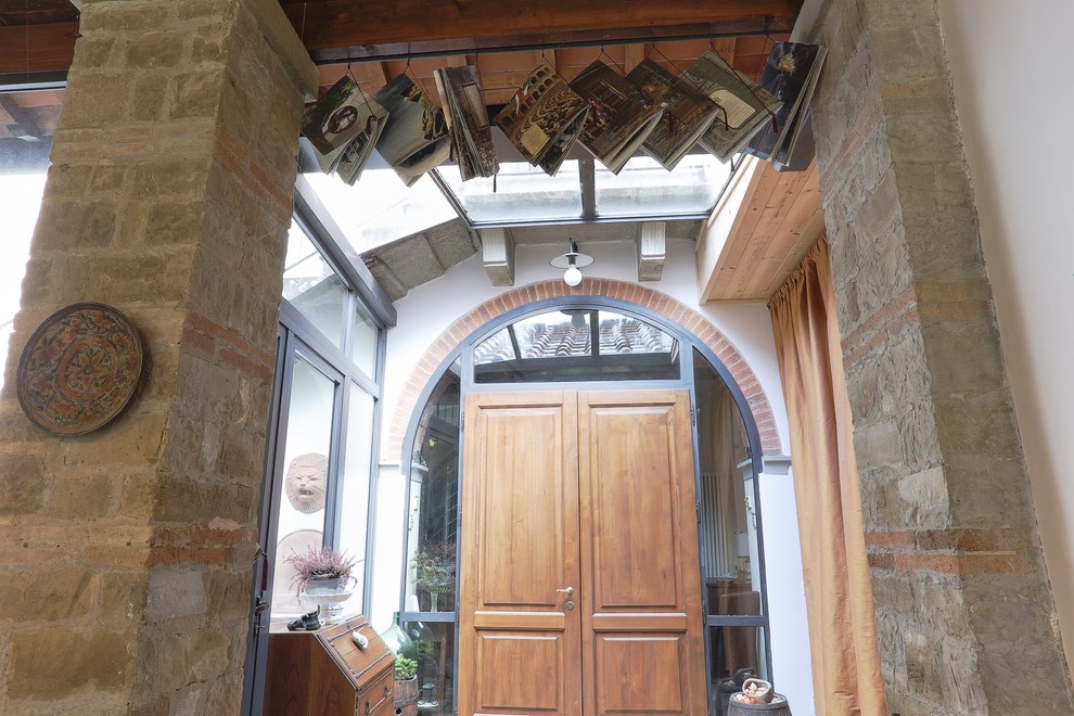 Photo of a country entryway in Florence with pink walls, a single front door and a light wood front door.