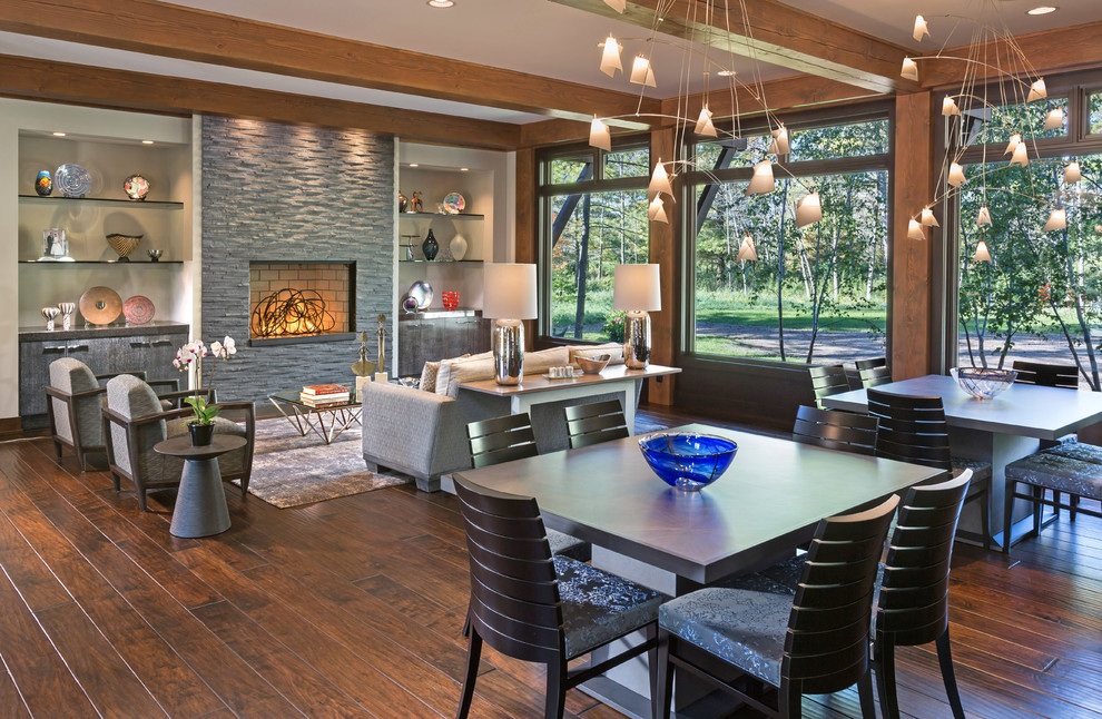 Inspiration for an expansive traditional open plan dining in Milwaukee with medium hardwood floors, a standard fireplace, a stone fireplace surround and grey walls.