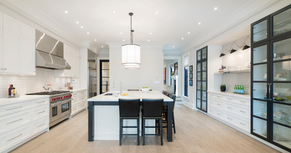 Open concept kitchen - transitional galley beige floor open concept kitchen idea in Toronto with an undermount sink, shaker cabinets, white cabinets, white backsplash, subway tile backsplash, stainless steel appliances and an island