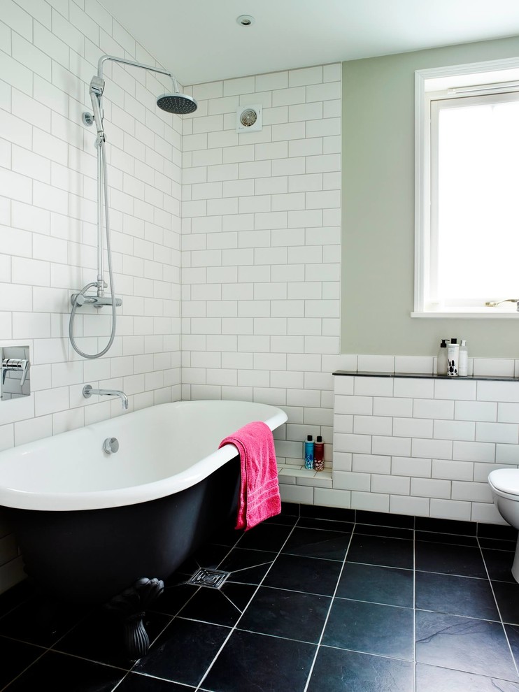 Design ideas for a traditional bathroom in London with a claw-foot tub, white tile, subway tile, white walls and black floor.