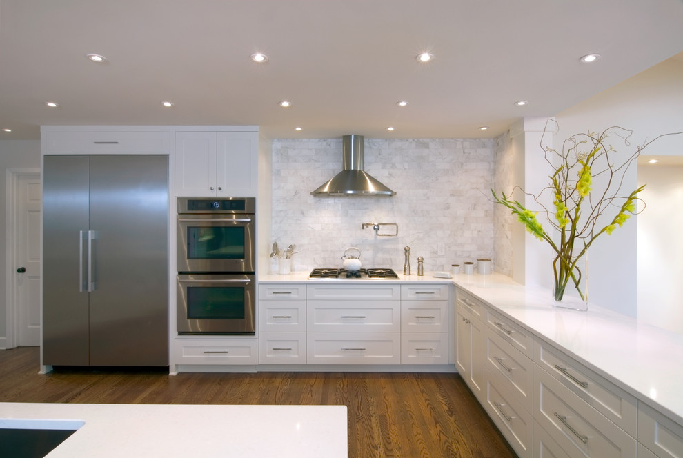 Design ideas for a large transitional l-shaped open plan kitchen in Portland with quartz benchtops, white splashback, white cabinets, shaker cabinets, stainless steel appliances, an undermount sink, marble splashback, medium hardwood floors, brown floor and with island.